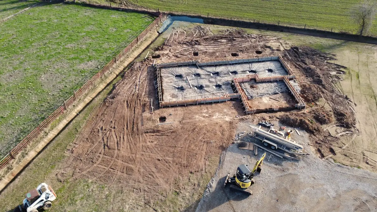 Terrain décapé en pleine campagne, engins de chantier près des fondations