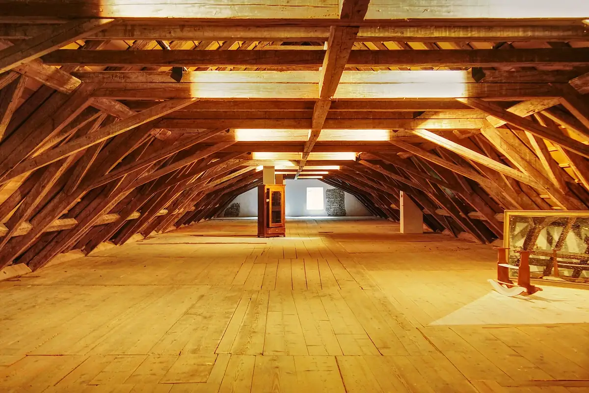 Vaste comble sous une charpente de bois, plancher clair et lumière chaude