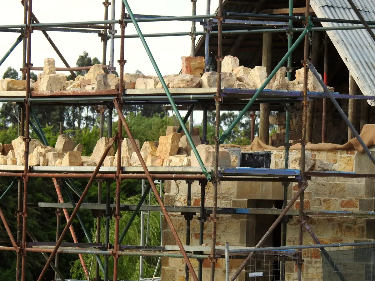 Échafaudage dressé contre un mur de pierre en cours de restauration