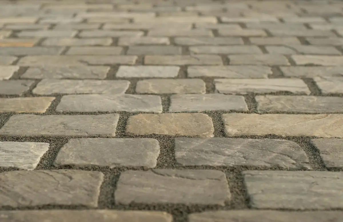 Pavés de pierre posés en rangées régulières, joints garnis de sable