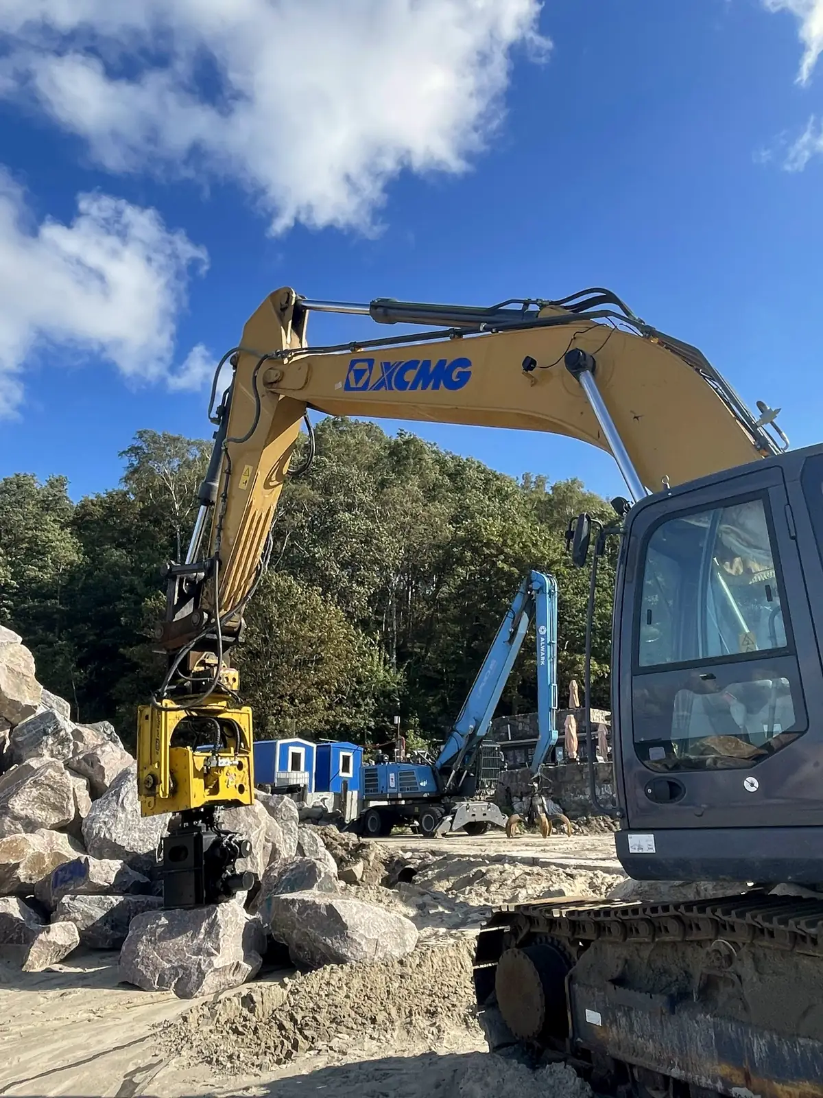 Pelle mécanique équipée d’un brise-roche hydraulique au milieu de blocs de pierre