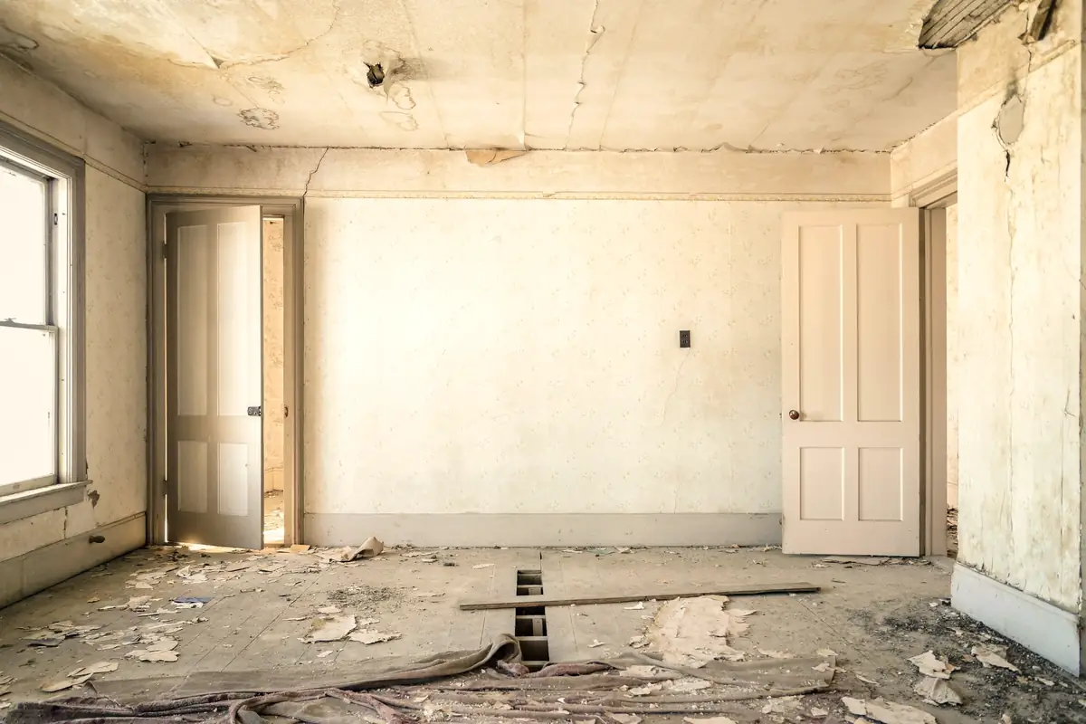 Pièce ancienne mise à nu avant travaux, papier peint arraché et parquet poussiéreux