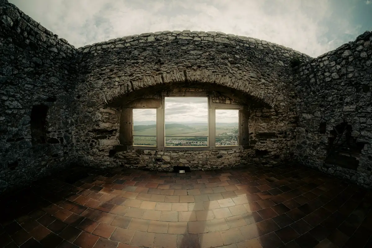 Pièce aux murs de pierre et sol de terre cuite, baie cintrée ouverte sur la campagne