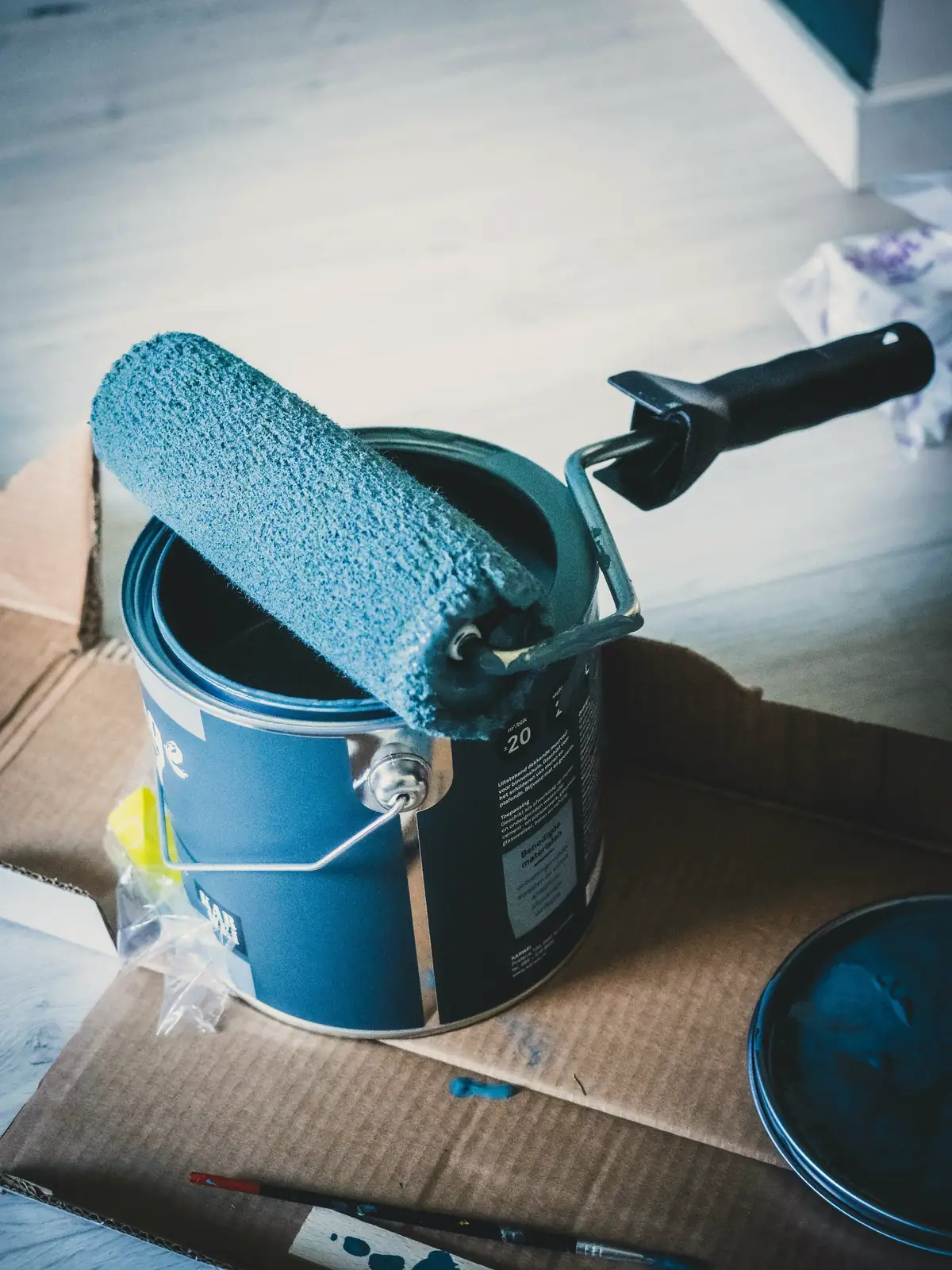 Rouleau chargé de peinture bleue posé en travers de son pot