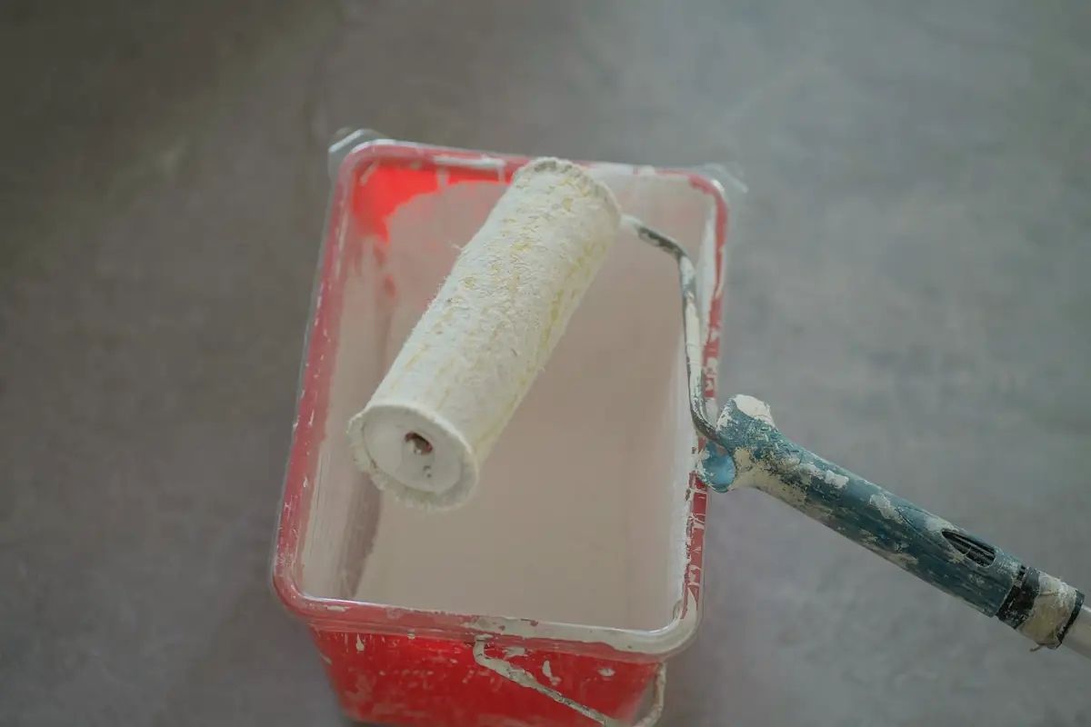 Rouleau de peintre posé dans un seau de peinture blanche