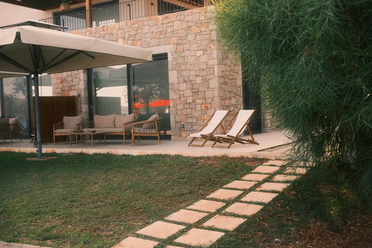 Terrasse dallée au pied d’une maison en pierre, pas japonais dans la pelouse
