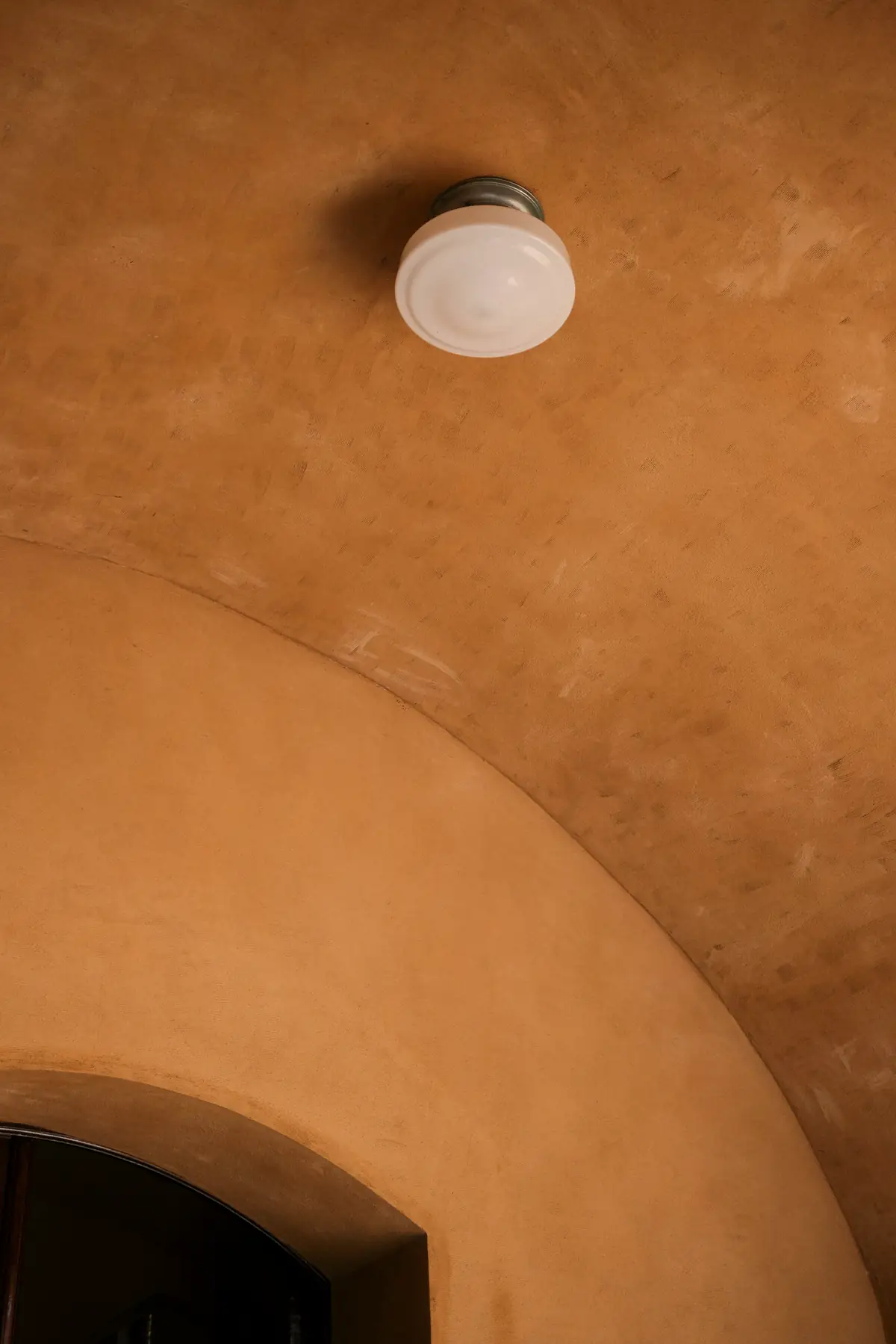 Plafond cintré enduit dans des tons ocre, plafonnier rond